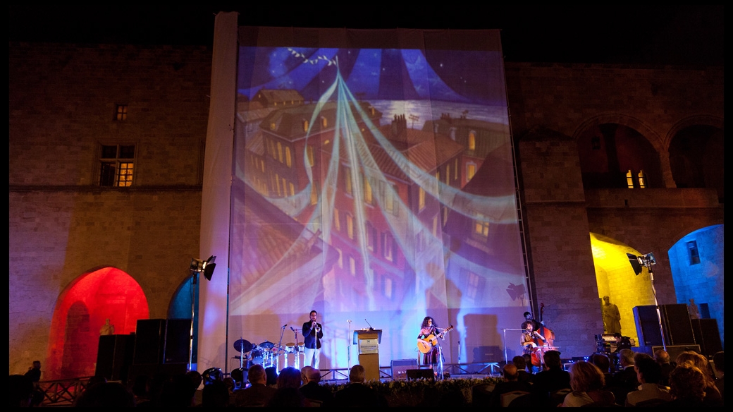Mona Caron artwork projected behind Rupa and The April Fishes during concert in Rhodes, Greece