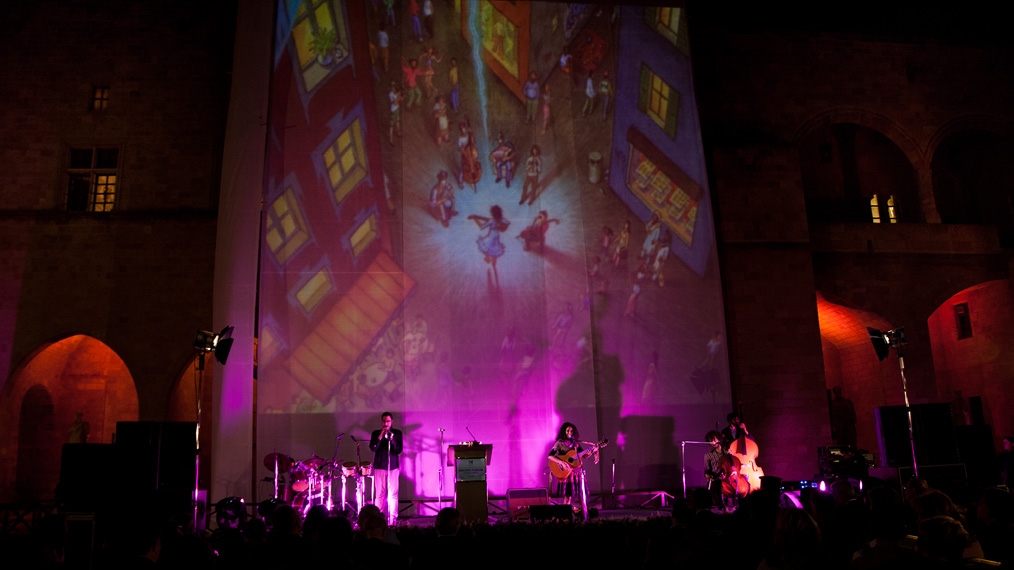 Rupa & The April Fishes in concert in Greece, with Mona Caron artwork projected as backdrop