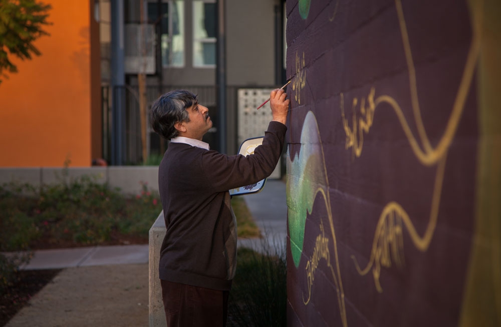 Local residents contributing words of welcome to the mural, in their native languages