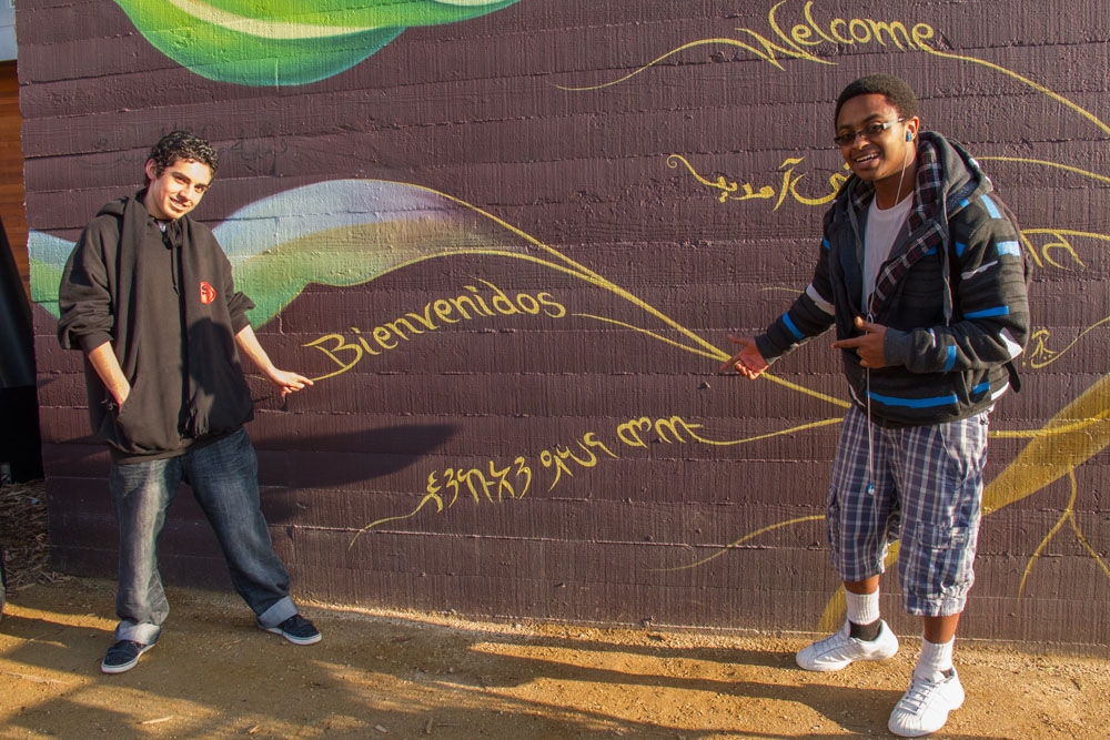 Local residents contributing words of welcome to the mural, in their native languages